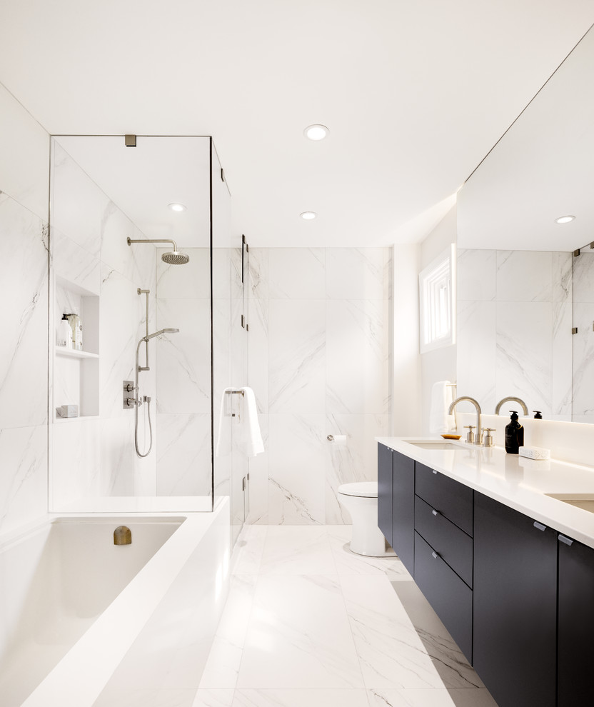 Aménagement d'une salle de bain principale contemporaine avec un placard à porte plane, des portes de placard noires, une baignoire posée, une douche d'angle, un carrelage noir et blanc, un carrelage gris, un carrelage blanc, un mur blanc, un lavabo encastré, un sol blanc et une cabine de douche à porte battante.