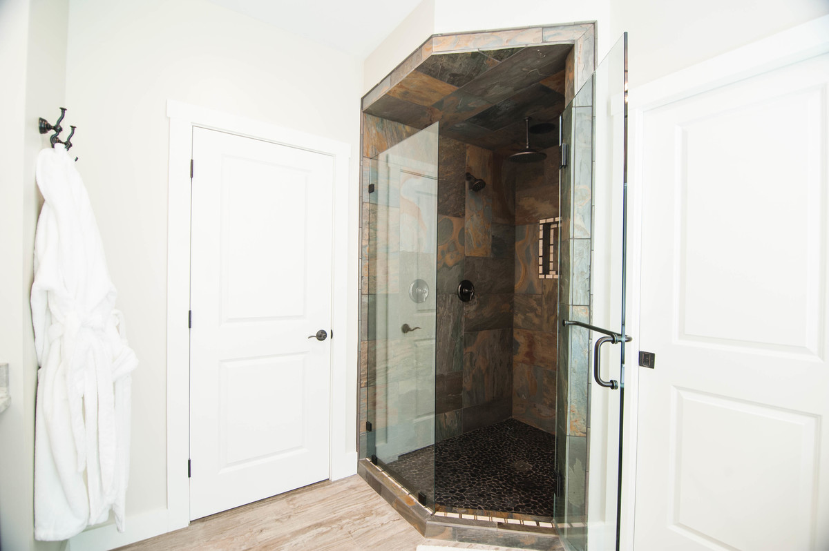 Inspiration for a medium sized classic ensuite bathroom in Portland Maine with recessed-panel cabinets, dark wood cabinets, a claw-foot bath, a corner shower, a one-piece toilet, multi-coloured tiles, slate tiles, grey walls, ceramic flooring, a submerged sink, granite worktops, beige floors and a hinged door.