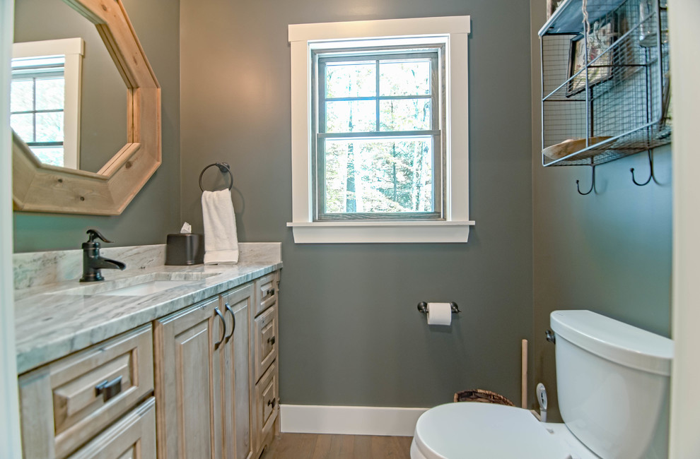 Kleines Uriges Badezimmer mit profilierten Schrankfronten, hellen Holzschränken, grüner Wandfarbe, braunem Holzboden, Granit-Waschbecken/Waschtisch und braunem Boden in Portland Maine