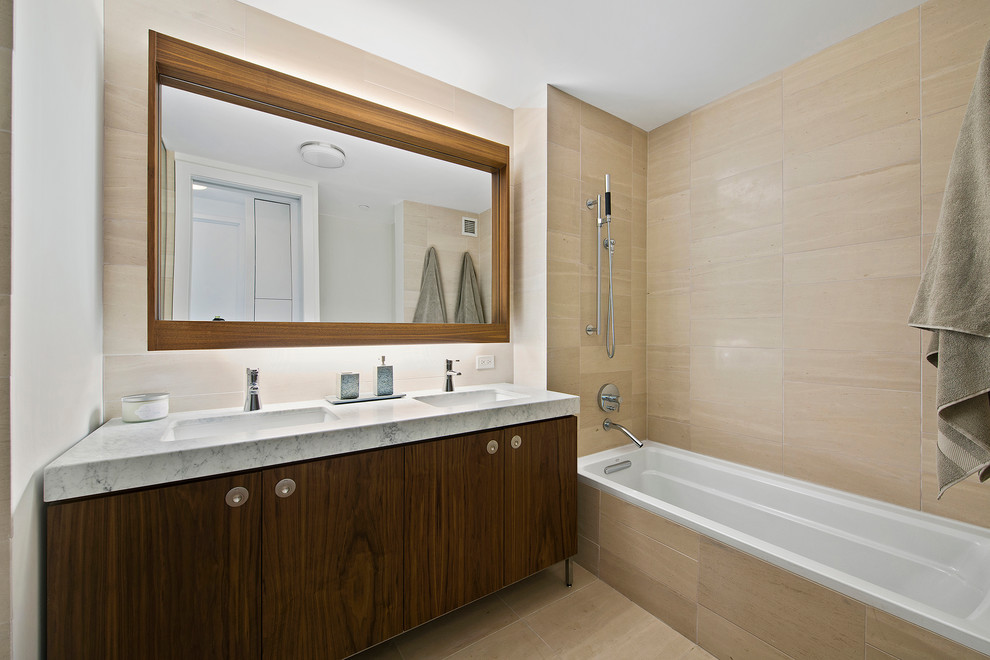 Exemple d'une salle de bain tendance en bois foncé avec un placard à porte plane, une baignoire posée, un combiné douche/baignoire, un carrelage beige, des carreaux de porcelaine, un sol en carrelage de porcelaine, un lavabo encastré et un plan de toilette en marbre.