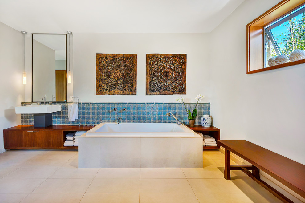 Asiatisk inredning av ett en-suite badrum, med släta luckor, skåp i mellenmörkt trä, ett platsbyggt badkar, blå kakel, mosaik, vita väggar och beiget golv