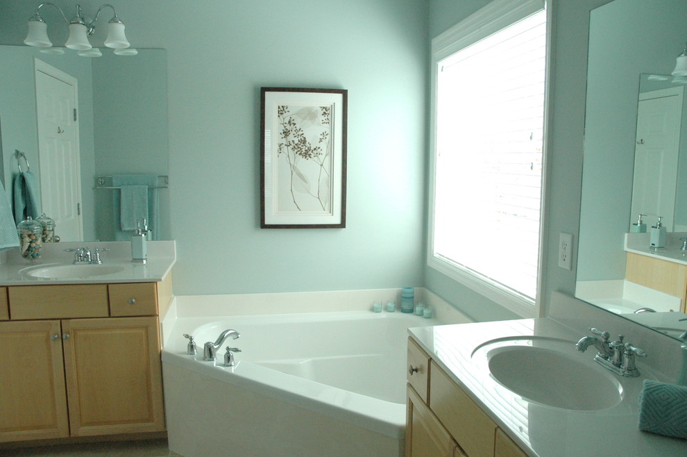 Imagen de cuarto de baño principal actual pequeño con puertas de armario de madera clara, bañera esquinera y paredes azules
