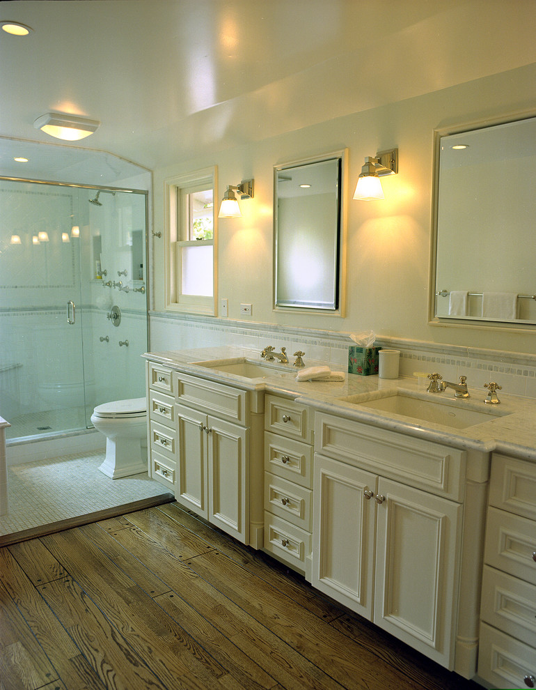 Foto på ett vintage badrum, med ett undermonterad handfat, luckor med infälld panel, beige skåp, en dusch i en alkov och vit kakel