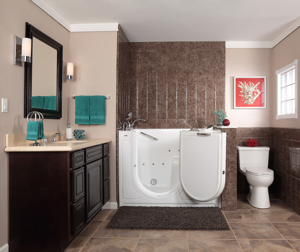 Mid-sized elegant master brown tile and porcelain tile porcelain tile bathroom photo in Austin with an undermount sink, raised-panel cabinets, dark wood cabinets, solid surface countertops, a two-piece toilet and beige walls