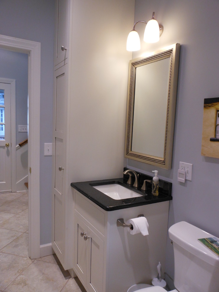 Cette photo montre une petite salle d'eau chic avec un lavabo encastré, un placard à porte affleurante, des portes de placard blanches, un plan de toilette en granite, WC séparés, un mur bleu et un sol en terrazzo.