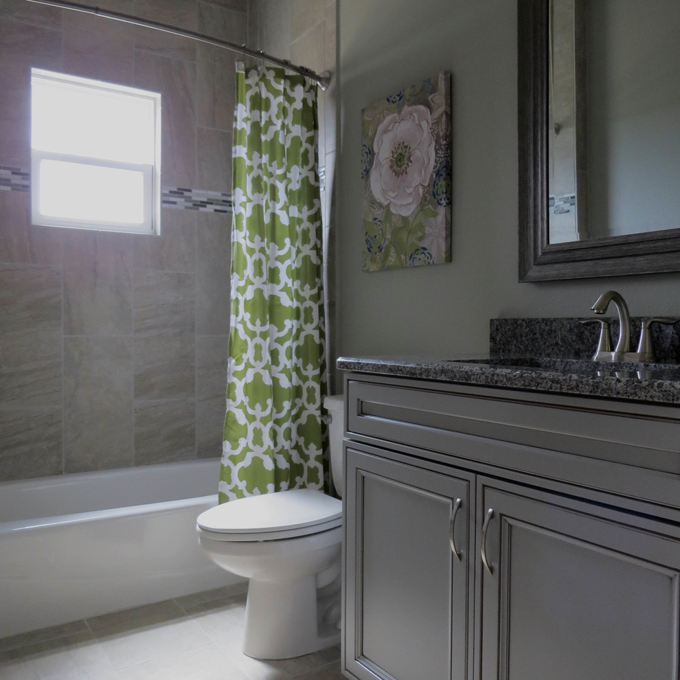 Medium sized rural bathroom in Atlanta with recessed-panel cabinets, grey cabinets, a built-in bath, a shower/bath combination, a one-piece toilet, grey walls, ceramic flooring, a submerged sink, granite worktops and a shower curtain.