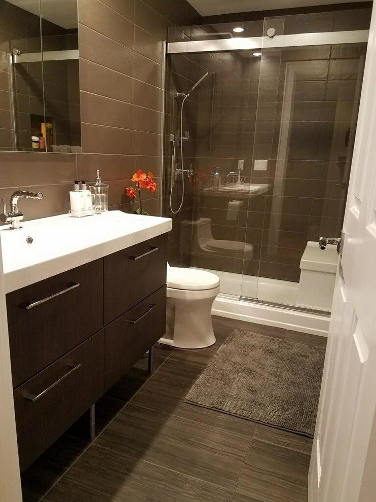 Medium sized classic shower room bathroom in New York with flat-panel cabinets, dark wood cabinets, an alcove shower, a one-piece toilet, brown tiles, porcelain tiles, brown walls, porcelain flooring, an integrated sink, solid surface worktops, brown floors and a sliding door.