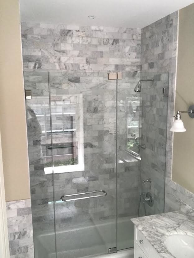 Photo of a medium sized classic shower room bathroom in New York with recessed-panel cabinets, grey cabinets, an alcove bath, a shower/bath combination, a two-piece toilet, grey tiles, white tiles, stone tiles, grey walls, a submerged sink, marble worktops and a hinged door.