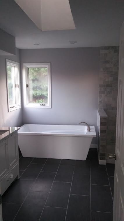 Diseño de cuarto de baño principal clásico renovado pequeño con puertas de armario blancas, bañera exenta, ducha abierta, baldosas y/o azulejos grises, paredes grises, lavabo encastrado y encimera de granito