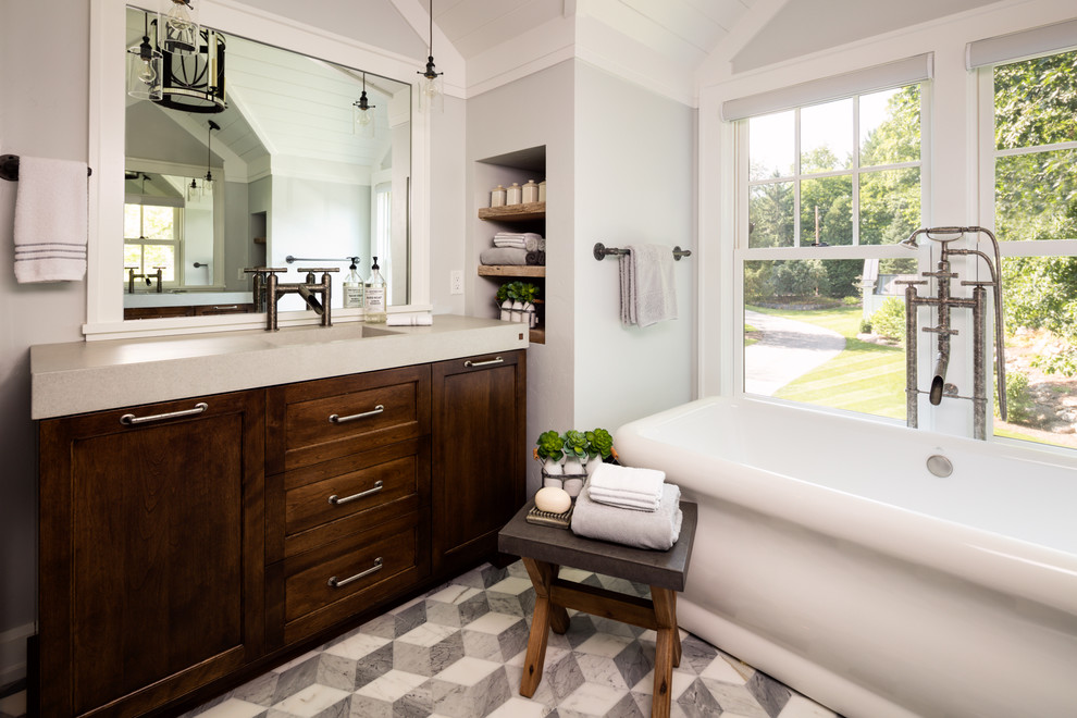 Cette image montre une salle de bain rustique en bois foncé avec un placard à porte shaker, une baignoire indépendante, un mur gris et un lavabo intégré.