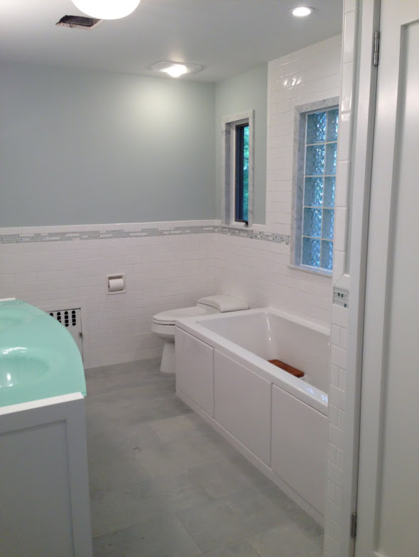 Inspiration pour une salle d'eau traditionnelle de taille moyenne avec un placard en trompe-l'oeil, des portes de placard blanches, une baignoire posée, un combiné douche/baignoire, un carrelage bleu, un carrelage gris, un carrelage blanc, un carrelage métro, un mur blanc, un lavabo intégré, un plan de toilette en verre et un sol gris.