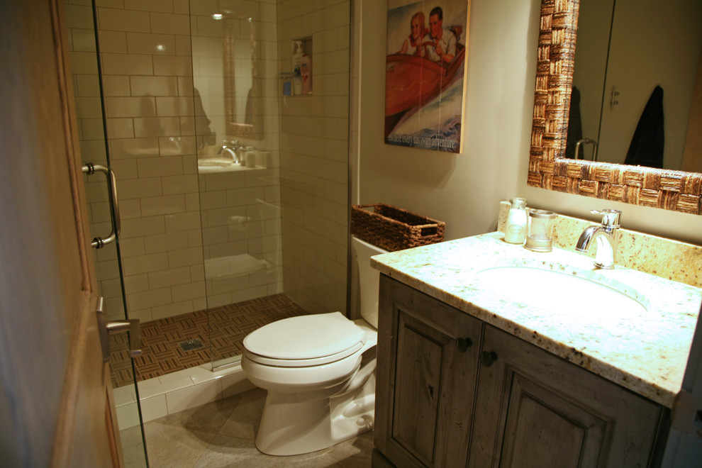 Industriell inredning av ett litet badrum med dusch, med luckor med upphöjd panel, skåp i slitet trä, granitbänkskiva, en öppen dusch, brun kakel, porslinskakel och travertin golv
