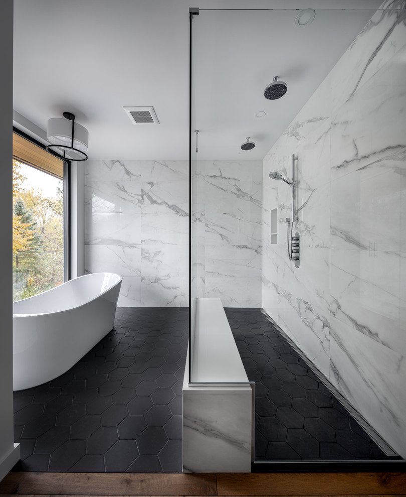 Cette image montre une salle de bain principale design avec une baignoire indépendante, une douche à l'italienne, un carrelage blanc, un mur blanc et un sol gris.