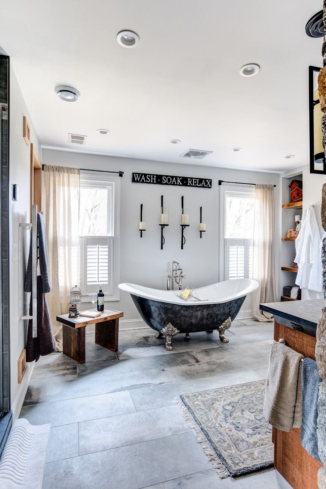 This is an example of a large rustic ensuite bathroom in New York with shaker cabinets, light wood cabinets, a walk-in shower, a one-piece toilet, grey tiles, cement tiles, grey walls, cement flooring, a submerged sink, granite worktops, grey floors, a sliding door and a claw-foot bath.