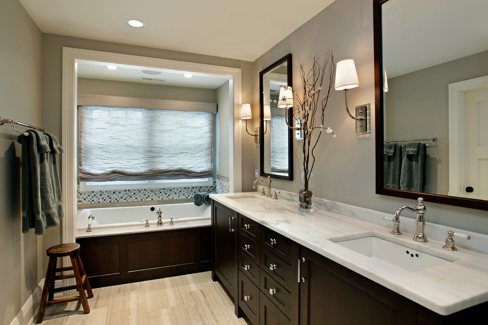 Imagen de cuarto de baño de estilo americano de tamaño medio con lavabo bajoencimera, armarios con paneles empotrados, puertas de armario de madera en tonos medios, bañera encastrada y ducha empotrada