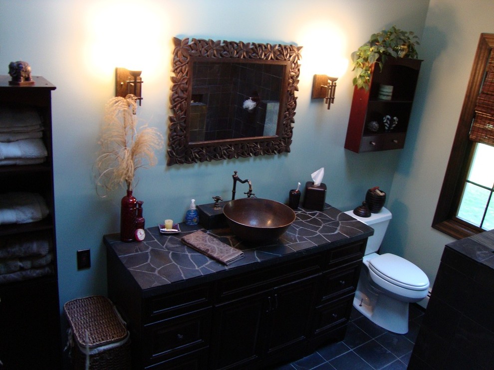 На фото: ванная комната в средиземноморском стиле с настольной раковиной, фасадами островного типа, темными деревянными фасадами, столешницей из плитки, накладной ванной, открытым душем, раздельным унитазом, синей плиткой и каменной плиткой