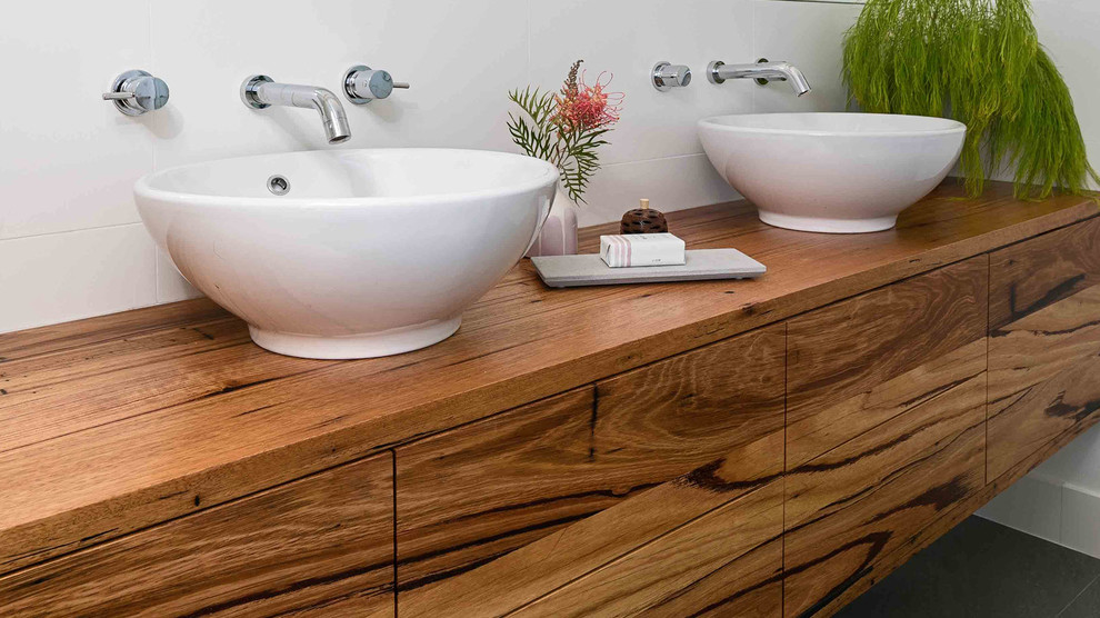Esempio di una stanza da bagno design con ante in legno scuro, piastrelle bianche, piastrelle in ceramica, lavabo a bacinella e top in legno