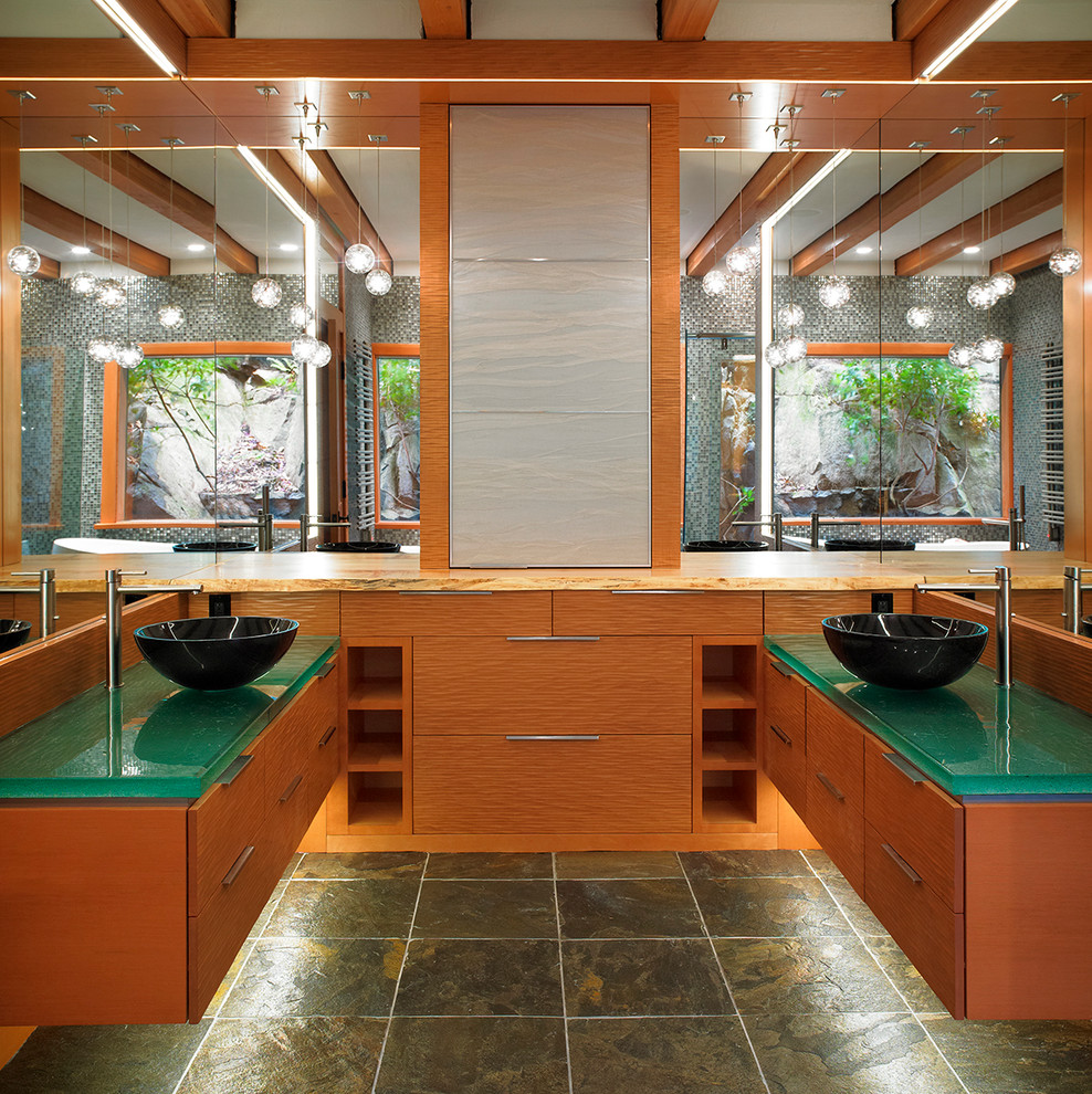 Immagine di una grande stanza da bagno padronale minimalista con ante lisce, ante in legno scuro, pareti grigie, pavimento in ardesia, lavabo a bacinella, top in vetro e pavimento grigio