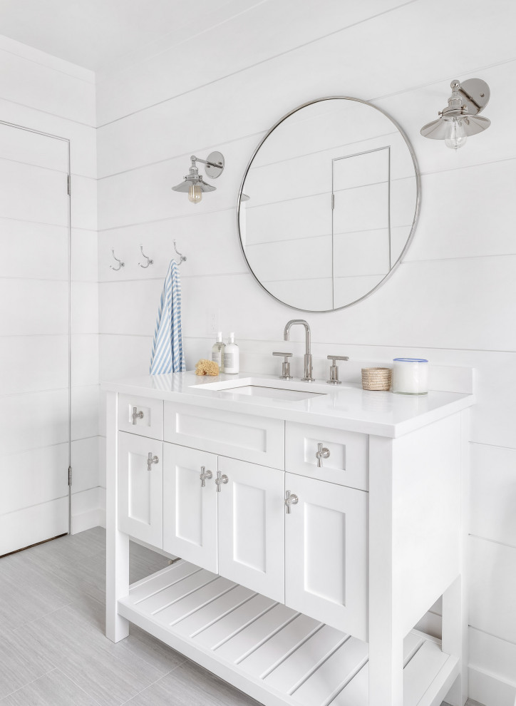 Exemple d'une salle de bain bord de mer avec un placard à porte shaker, des portes de placard blanches, un mur blanc, un sol gris, un plan de toilette blanc, meuble simple vasque, meuble-lavabo sur pied et du lambris de bois.