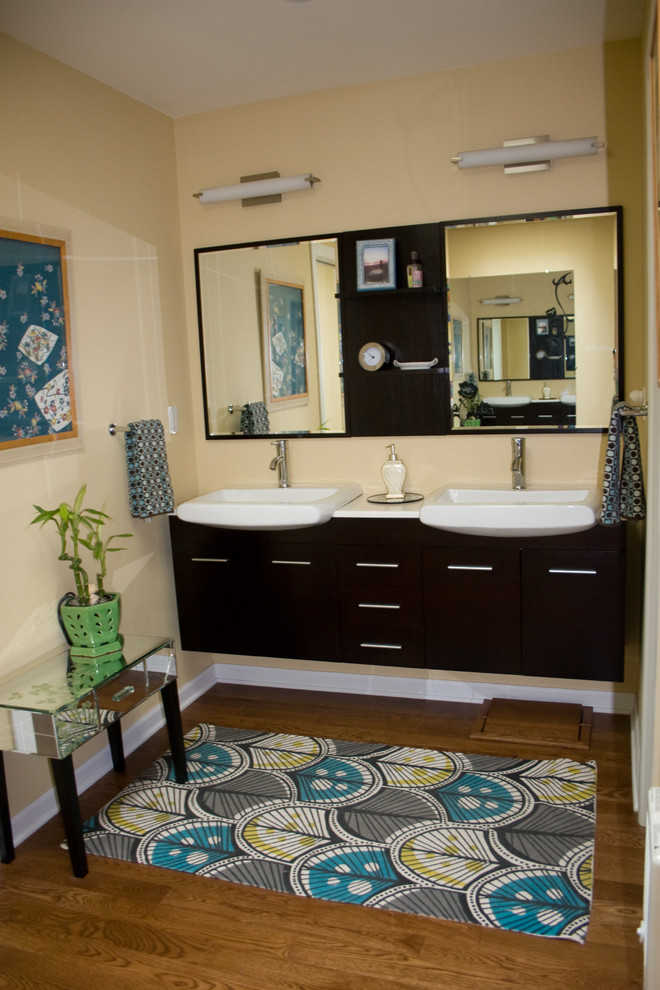 На фото: большая главная ванная комната в стиле неоклассика (современная классика) с плоскими фасадами, черными фасадами, желтыми стенами, паркетным полом среднего тона, настольной раковиной, столешницей из искусственного кварца и коричневым полом