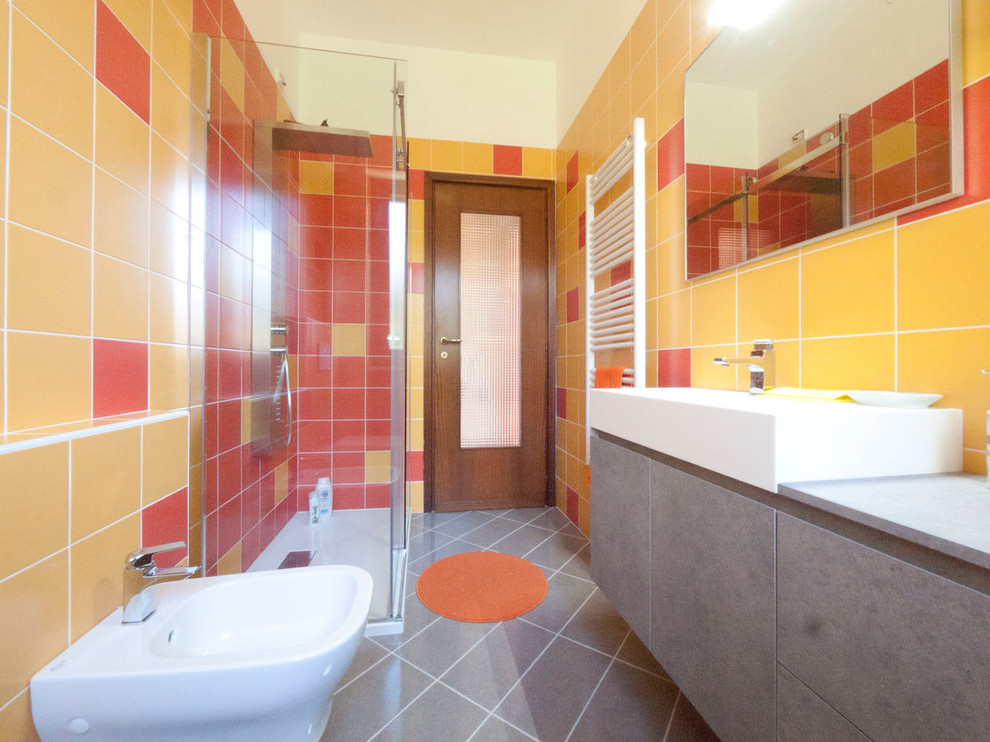 Modern inredning av ett mellanstort en-suite badrum, med ett konsol handfat, släta luckor, grå skåp, laminatbänkskiva, en hörndusch, en toalettstol med separat cisternkåpa, orange kakel, keramikplattor, orange väggar och klinkergolv i keramik