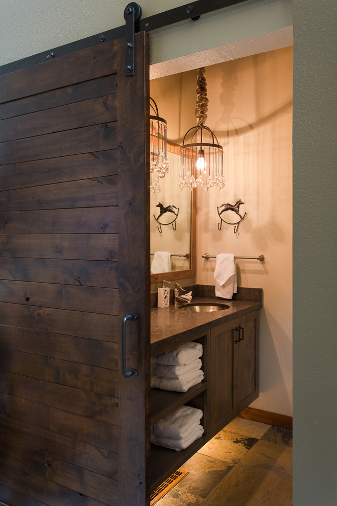 Modelo de cuarto de baño clásico con lavabo bajoencimera, puertas de armario grises, encimera de piedra caliza, paredes grises y suelo de pizarra