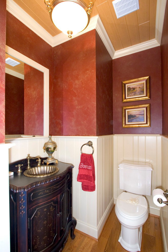 Пример оригинального дизайна: маленький туалет в классическом стиле с фасадами островного типа, темными деревянными фасадами, раздельным унитазом, красными стенами, светлым паркетным полом и накладной раковиной для на участке и в саду
