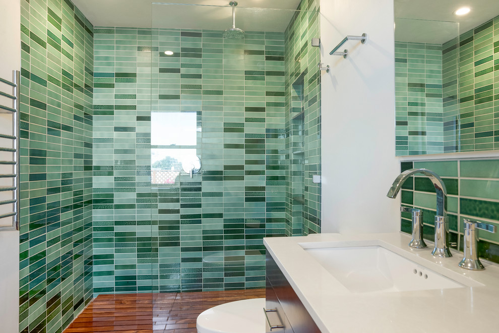 Inredning av ett mellanstort vit vitt en-suite badrum, med släta luckor, bruna skåp, en kantlös dusch, ett undermonterad handfat, med dusch som är öppen, grön kakel, keramikplattor och vita väggar