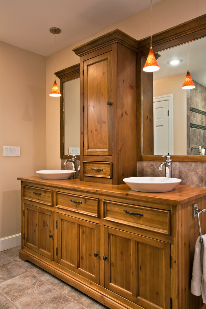 Inspiration for a large traditional ensuite bathroom in Boston with recessed-panel cabinets, medium wood cabinets, a built-in bath, a walk-in shower, beige tiles, ceramic tiles, beige walls, ceramic flooring, a vessel sink and wooden worktops.