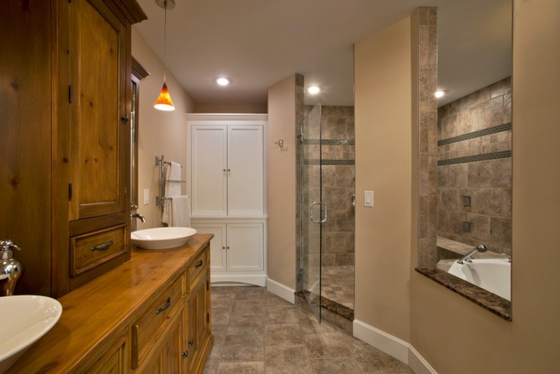 Cette image montre une grande salle de bain principale traditionnelle en bois brun avec un placard avec porte à panneau encastré, une baignoire posée, une douche ouverte, un carrelage beige, des carreaux de céramique, un mur beige, un sol en carrelage de céramique, une vasque et un plan de toilette en bois.