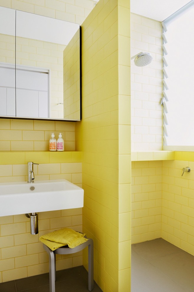 Idéer för att renovera ett litet funkis badrum, med ett väggmonterat handfat, släta luckor, en dusch i en alkov, en vägghängd toalettstol, gul kakel, keramikplattor, gula väggar och klinkergolv i keramik
