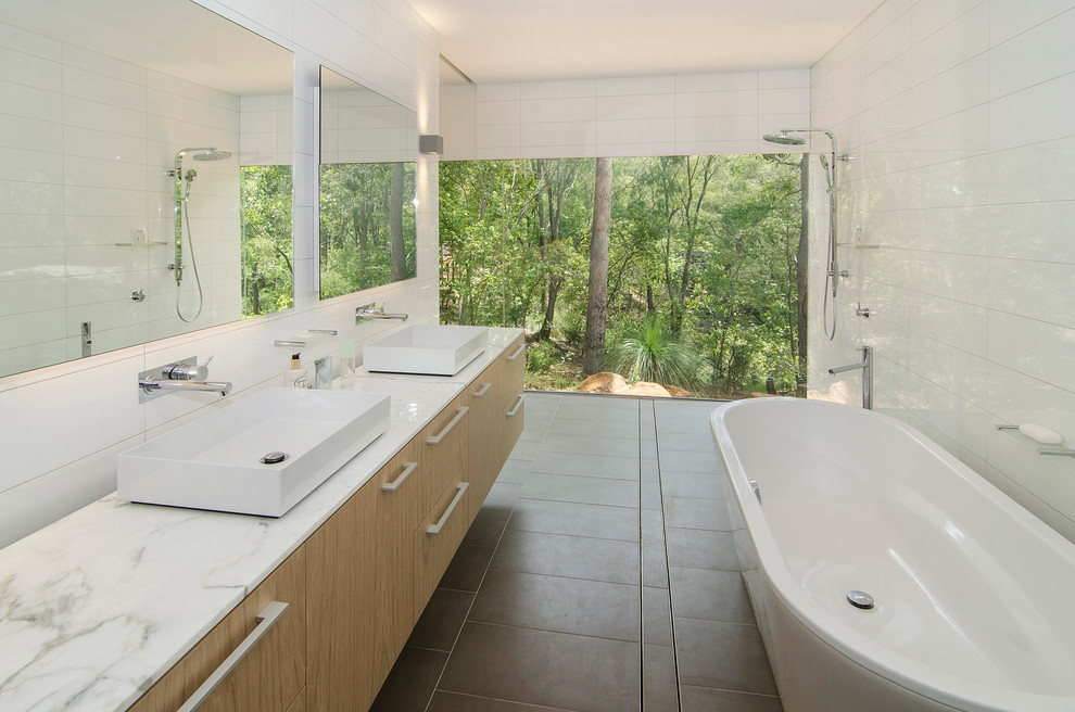 Пример оригинального дизайна: главная ванная комната в современном стиле с белой плиткой, белыми стенами, настольной раковиной, плоскими фасадами, фасадами цвета дерева среднего тона, отдельно стоящей ванной и душем без бортиков