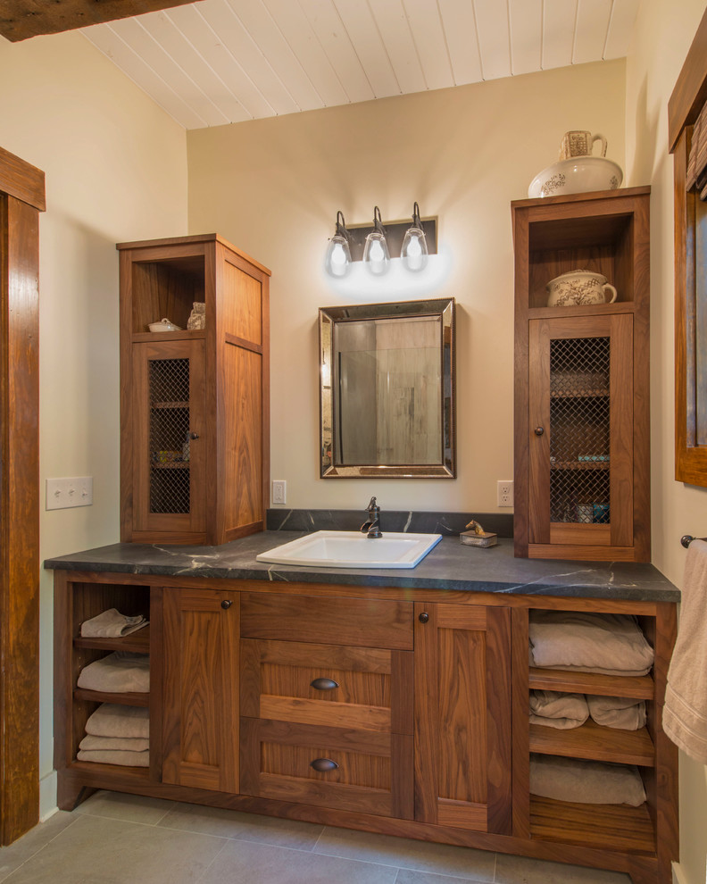 Bild på ett litet lantligt badrum, med ett nedsänkt handfat, luckor med infälld panel, skåp i mellenmörkt trä, beige väggar, skiffergolv och bänkskiva i täljsten