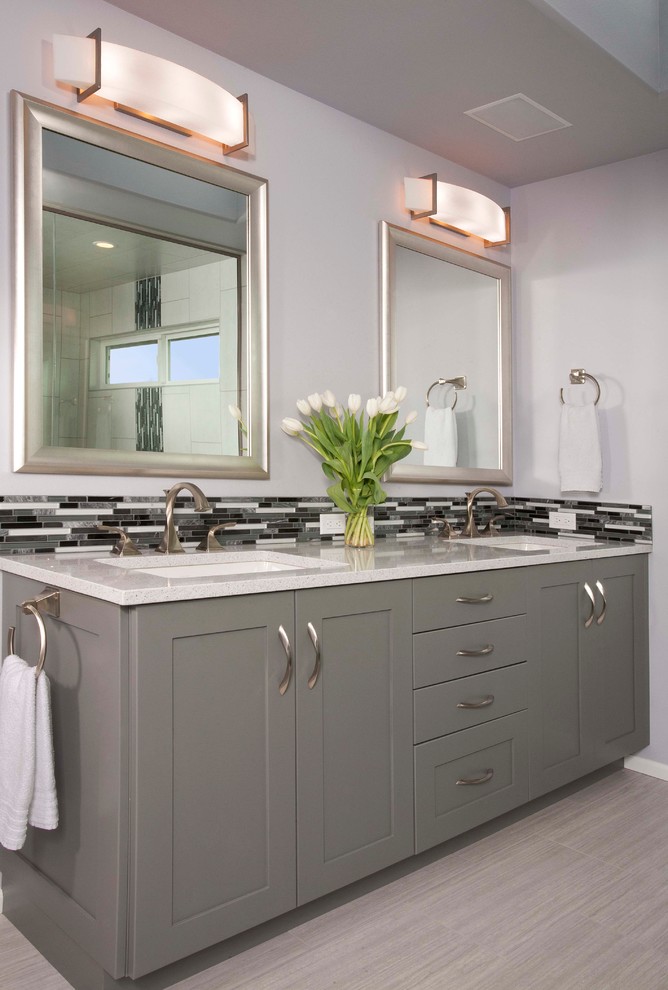 This is an example of a large traditional ensuite bathroom in Seattle with a submerged sink, shaker cabinets, grey cabinets, engineered stone worktops, a freestanding bath, a shower/bath combination, a two-piece toilet, grey tiles, porcelain tiles, grey walls and porcelain flooring.