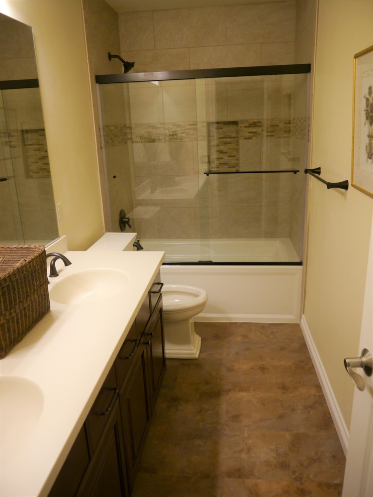 Пример оригинального дизайна: ванная комната среднего размера в классическом стиле с фасадами с выступающей филенкой, коричневыми фасадами, душем над ванной, раздельным унитазом, бежевой плиткой, керамической плиткой, желтыми стенами, полом из керамической плитки, монолитной раковиной, коричневым полом, душем с раздвижными дверями и белой столешницей