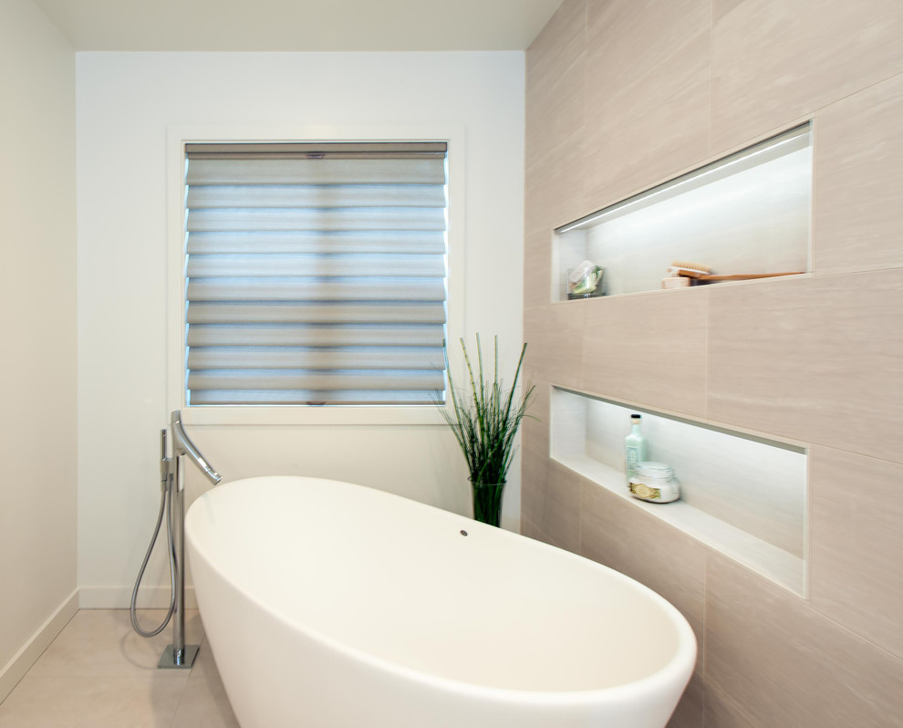 Cette image montre une grande salle de bain principale minimaliste avec une baignoire indépendante, un carrelage gris et un mur blanc.