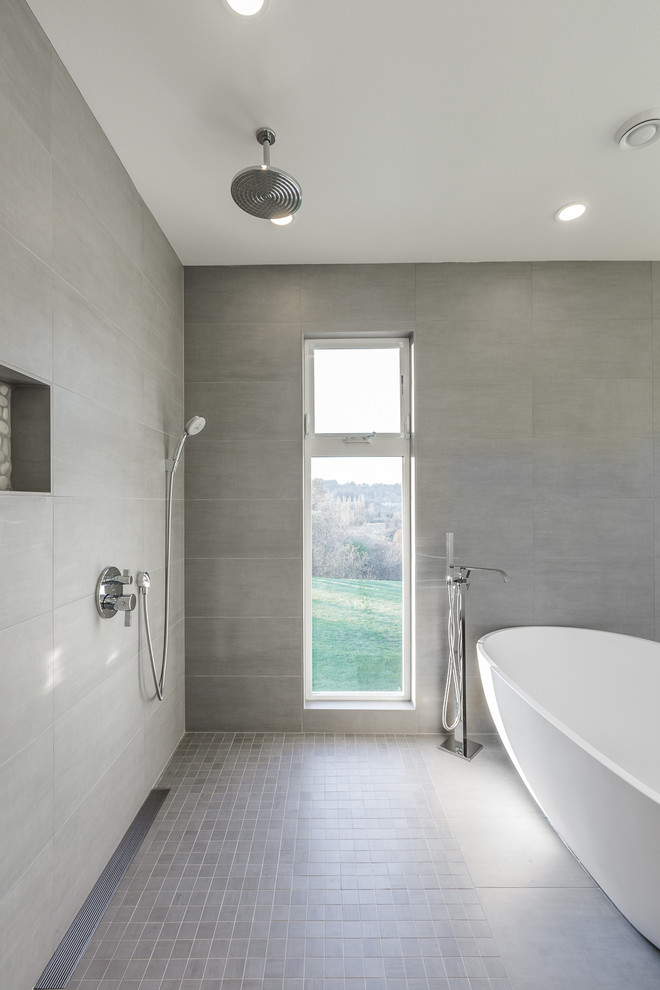 Idee per una stanza da bagno minimal con vasca freestanding, piastrelle grigie e pavimento con piastrelle a mosaico