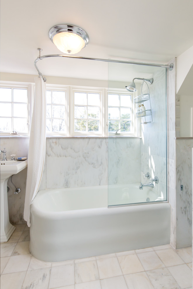 Inredning av ett lantligt mellanstort en-suite badrum, med vita skåp, ett hörnbadkar, en dusch/badkar-kombination, en toalettstol med separat cisternkåpa, grå kakel, vit kakel, marmorkakel, vita väggar, marmorgolv, ett piedestal handfat, vitt golv och dusch med duschdraperi