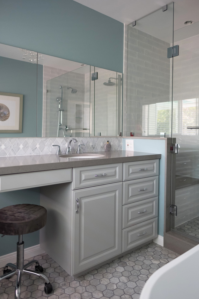 Design ideas for a medium sized coastal ensuite bathroom in Los Angeles with raised-panel cabinets, grey cabinets, a freestanding bath, a double shower, a one-piece toilet, white tiles, metro tiles, blue walls, marble flooring, a submerged sink, grey floors, a hinged door and grey worktops.