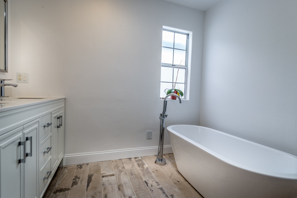 Réalisation d'une salle de bain principale minimaliste de taille moyenne avec des portes de placard blanches, une baignoire indépendante, un placard à porte shaker, un mur blanc et un lavabo encastré.