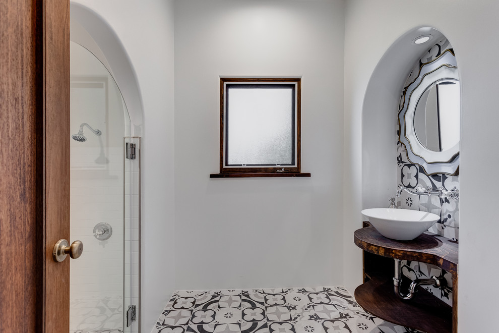 Пример оригинального дизайна: ванная комната среднего размера в стиле неоклассика (современная классика) с открытыми фасадами, темными деревянными фасадами, разноцветной плиткой, терракотовой плиткой, белыми стенами, настольной раковиной, столешницей из дерева, душевой кабиной, душем в нише, полом из цементной плитки, разноцветным полом, душем с распашными дверями и коричневой столешницей