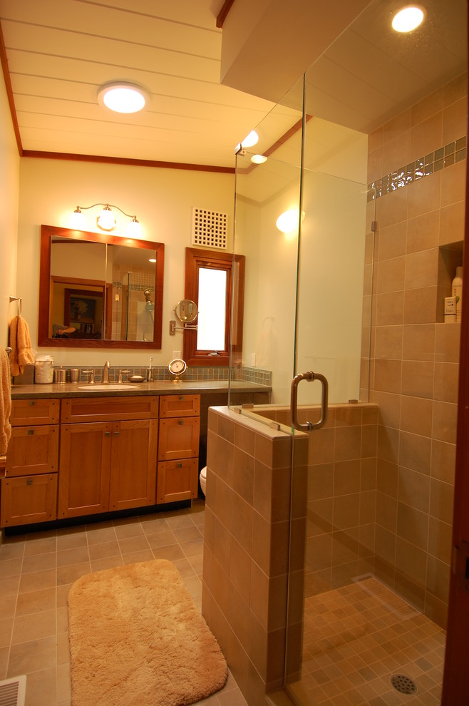 На фото: большая ванная комната в стиле кантри с врезной раковиной, фасадами цвета дерева среднего тона, столешницей из известняка, угловым душем, бежевой плиткой, керамической плиткой, белыми стенами и полом из керамической плитки с