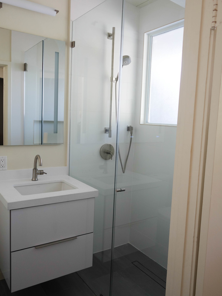 Medium sized retro shower room bathroom in San Francisco with flat-panel cabinets, white cabinets, an alcove shower, a two-piece toilet, white tiles, porcelain tiles, white walls, concrete flooring, a submerged sink, engineered stone worktops, grey floors, a hinged door and white worktops.