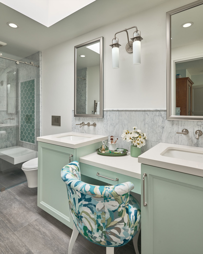 Foto på ett litet vintage vit en-suite badrum, med luckor med infälld panel, gröna skåp, en kantlös dusch, en vägghängd toalettstol, grå kakel, marmorkakel, vita väggar, klinkergolv i porslin, ett undermonterad handfat, bänkskiva i akrylsten, grått golv och dusch med skjutdörr