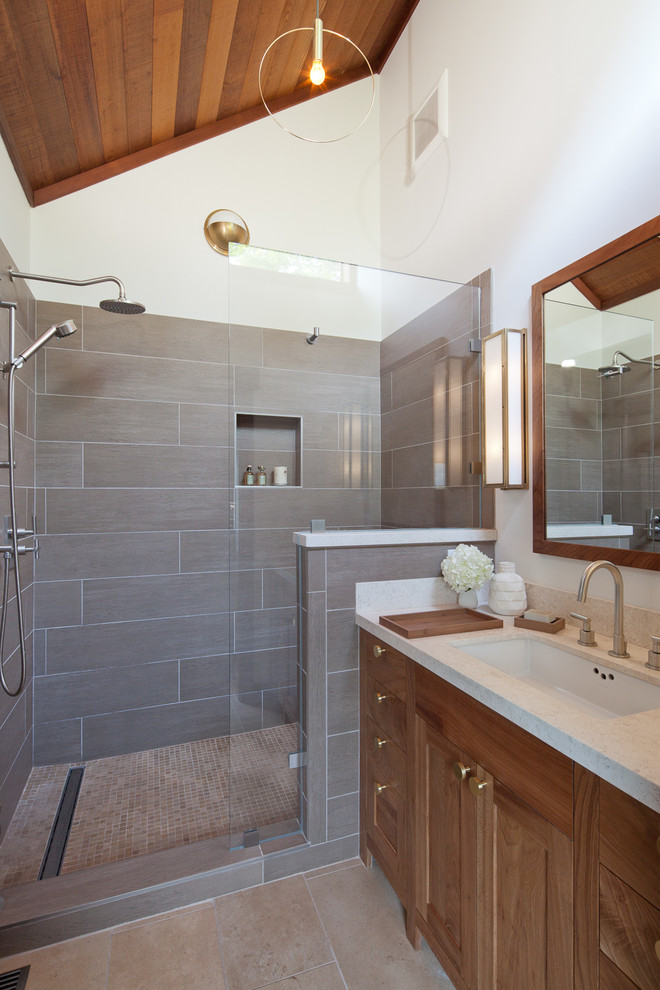 Exemple d'une salle de bain montagne en bois brun de taille moyenne avec un placard à porte shaker, un mur blanc, un sol en carrelage de porcelaine, un lavabo encastré, un plan de toilette en quartz modifié, un sol beige, une cabine de douche à porte battante et un plan de toilette beige.