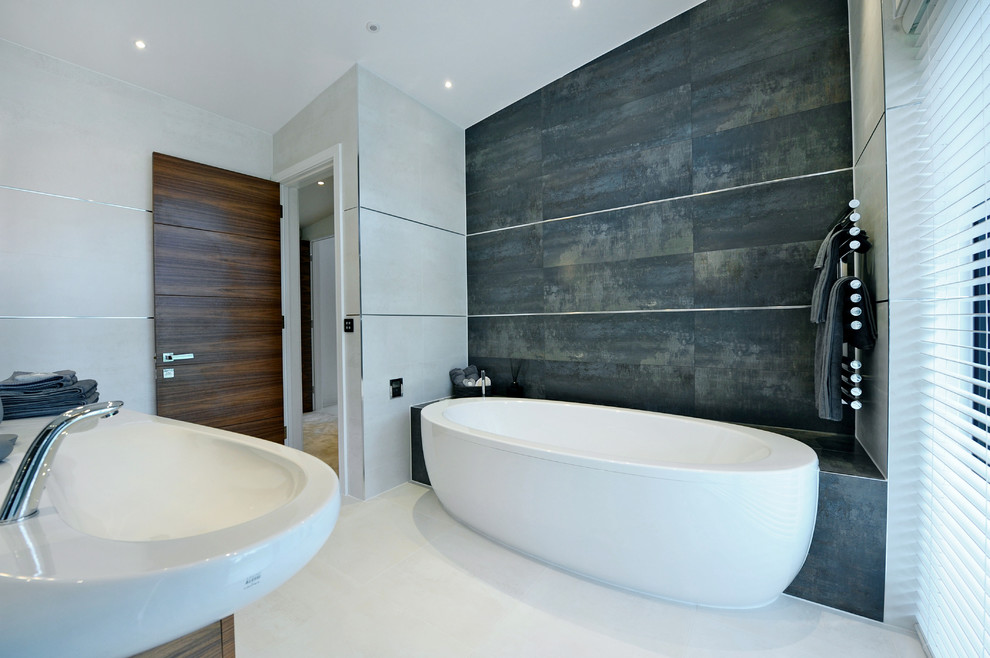 Aménagement d'une salle de bain contemporaine avec un lavabo suspendu, un carrelage gris, un mur blanc, un sol en carrelage de porcelaine et une baignoire indépendante.