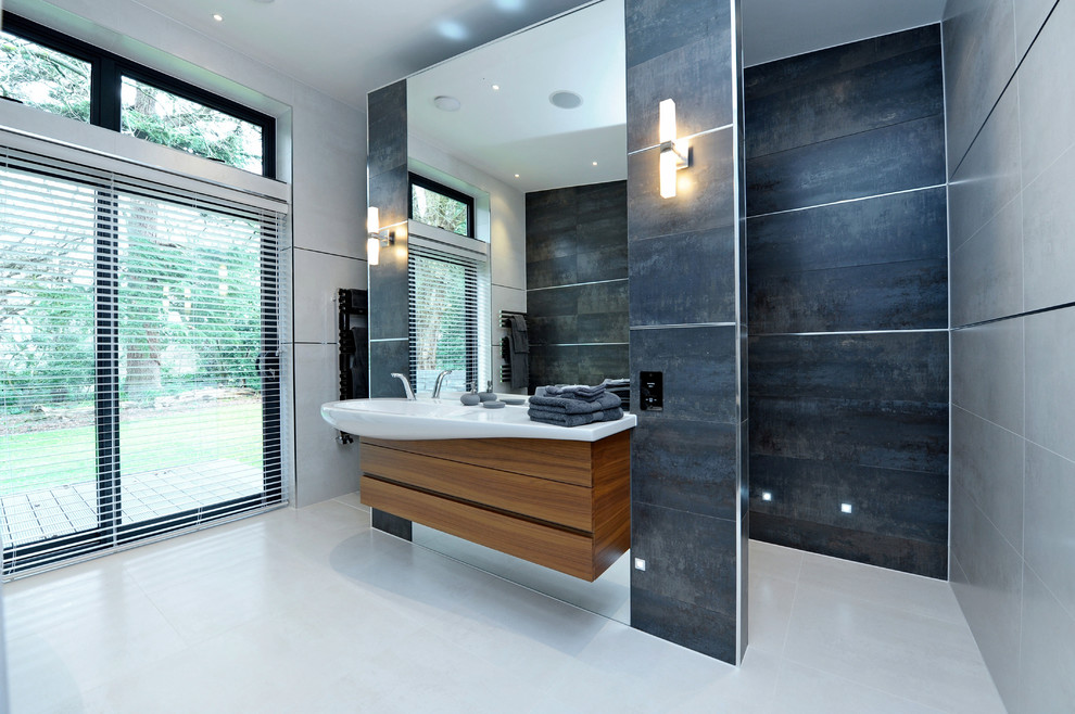 Modelo de cuarto de baño actual grande con puertas de armario de madera oscura y baldosas y/o azulejos grises