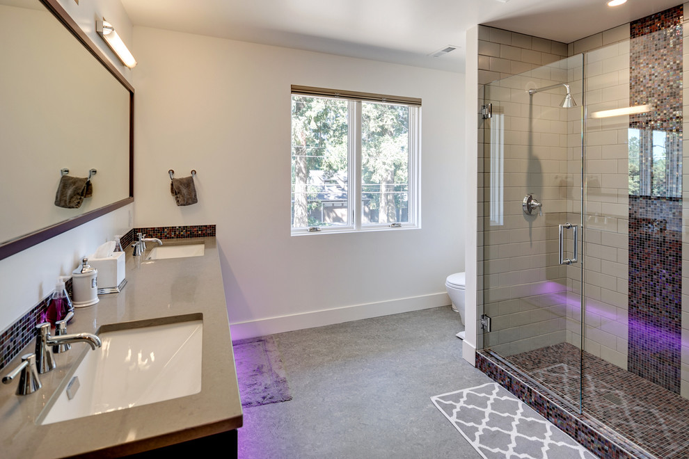 Alcove shower - mid-sized contemporary master black tile, brown tile and mosaic tile concrete floor and gray floor alcove shower idea in Portland with a one-piece toilet, white walls, an undermount sink, solid surface countertops and a hinged shower door