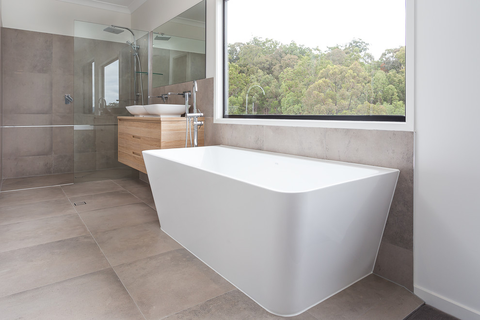 Photo of a medium sized contemporary ensuite bathroom in Gold Coast - Tweed with freestanding cabinets, light wood cabinets, wooden worktops, a freestanding bath, a corner shower, grey tiles, ceramic tiles, white walls, ceramic flooring and a vessel sink.