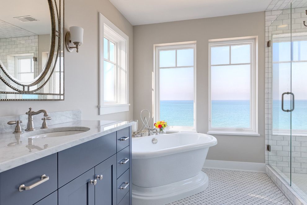 Источник вдохновения для домашнего уюта: ванная комната в морском стиле с фасадами в стиле шейкер, синими фасадами, отдельно стоящей ванной, угловым душем, желтой плиткой, мраморной плиткой, бежевыми стенами, полом из мозаичной плитки, монолитной раковиной, мраморной столешницей, белым полом и душем с распашными дверями
